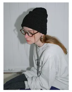 Close-up of black wool-blend knit beanie showing thick ribbed texture on model