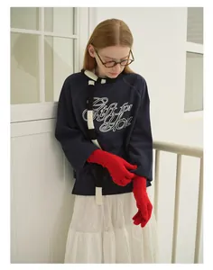 Detail of red knit warm gloves paired with a navy sweatshirt and striped scarf