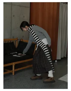 Retro striped long knit scarf styled with grey cable sweater and plaid skirt for winter