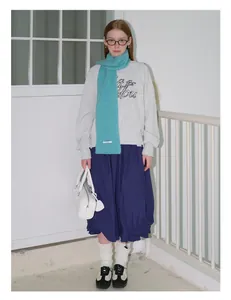 Detail van grijze sweater met blauwe midi-rok en blauwe gebreide wollen sjaal outfit