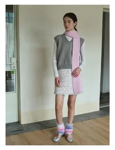 Detailed view of pink knitted wool scarf paired with a grey vest and tweed skirt set