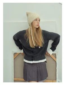 Detail of soft alpaca blend knit hat with long straps and gray rib-knit cardigan