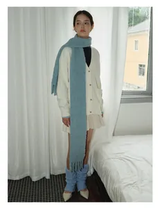 Blue chunky knit wool scarf with fringe styled with a beige cardigan and pleated skirt