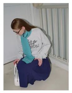 Detailopname van de pluizige turquoise wollen sjaal gecombineerd met een grijze sweater