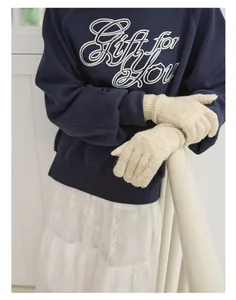 Detail view of winter warm cream knitted wool blend gloves paired with a blue sweatshirt