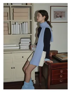 Close-up of light blue thick wool scarf with navy turtleneck and white pleated skirt