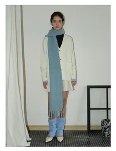 Detailed view of light blue wool blend tassel scarf paired with white knit cardigan
