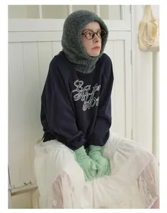 Winter balaclava hat paired with deep blue sweatshirt and mint green knit gloves