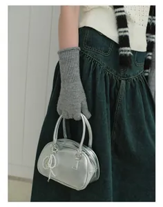 Detailed view of grey wool blend knit gloves paired with a silver pearl charm handbag