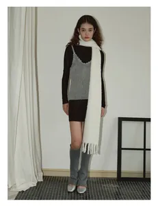 Full view of women wearing a white wool blend tassel scarf with grey leg warmers