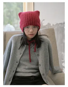 Macro detail of red alpaca wool knit hat with cat ears and braided strap ties