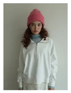 Vista frontal de sudadera blanca con media cremallera y un gorro de punto rosa suave
