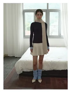 Full view of a soft beige wool scarf styled with a navy knit top and white pleated skirt