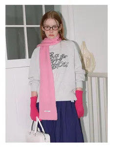 Detail van roze wollen sjaal met 82% wol label en grijs sweatshirt met opdruk