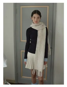 Detailed close-up of thick wool blend knit scarf with long tassels in creamy white color