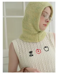 Close-up detail of soft textured wool blend balaclava and apple embroidery on knit vest