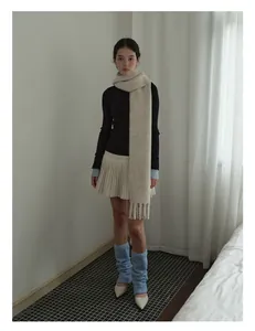 Styling of beige wool blend fringe scarf with black top and cream pleated skirt