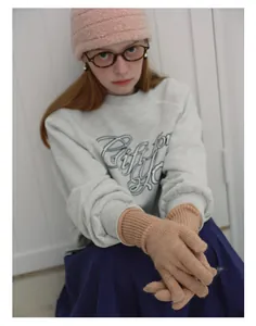 Detail of soft camel wool blend knit gloves worn with pink hat and gray sweatshirt