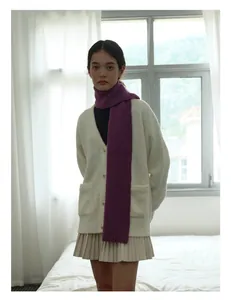Detail of soft dark purple wool scarf paired with a beige knit cardigan for winter