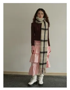 Detail of wool blend plaid scarf paired with tiered pink skirt and brown long sleeve top