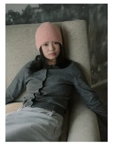 Gros plan d'un bonnet en laine rose à côtes porté par un mannequin dans un décor cosy