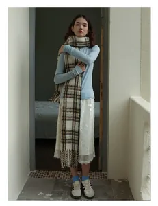 Detail of wool blend plaid scarf with classic tassels and soft beige check pattern
