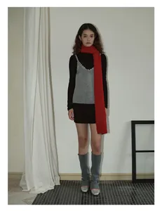 Full body view of a woman wearing a red wool scarf with a grey knit top and leg warmers