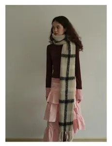 Detailed view of neutral plaid wool blend scarf with fringe edges and soft texture