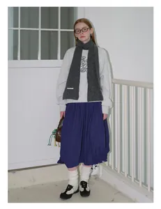 Detailansicht eines dunkelgrauen Strickschals kombiniert mit grauem Sweatshirt und Rock