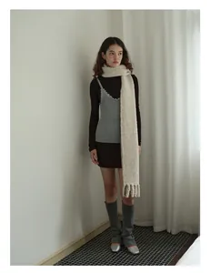 Detailed view of extra long off-white wool blend scarf with tassels on a female model