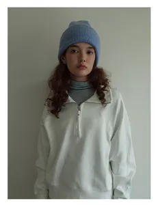 Primer plano de gorro de lana azul claro combinado con sudadera blanca de media cremallera
