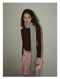 Full body view of a long grey chunky knit wool scarf paired with a stylish slim-fit top