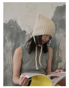 Detail of beige alpaca blend knit cat-ear hat with soft long ties and textured finish