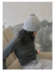 Détail du bonnet en maille côtelée gris clair et texture du cardigan en laine gris foncé
