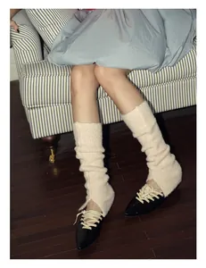 Close-up of cream wool blend balletcore leg warmers styled with black pointed shoes