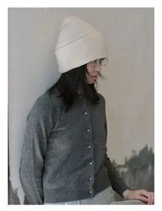 Detalle del gorro de punto acanalado 100% lana de oveja y cárdigan cálido en modelo mujer