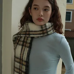 Classic neutral plaid wool blend scarf with warm colors worn over a light blue turtleneck sweater