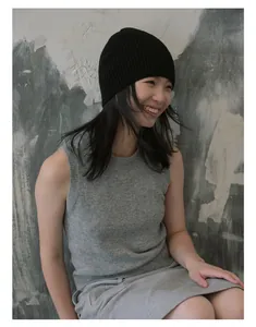 Détail d'un bonnet en tricot noir minimaliste associé à une tenue en maille grise
