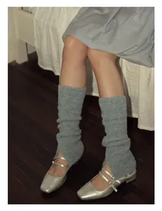 Close-up of ballet style wool-blend grey blue leg warmers with silver Mary Jane shoes