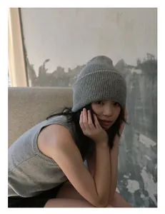 Detalle del gorro de punto de 100% lana de oveja gris y chaleco a juego con textura de canalé