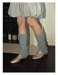 Close-up of light blue knit leg warmers paired with silver Mary Jane shoes in soft lighting
