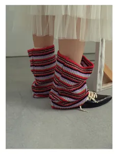 Detail of colorful striped wool blend leg warmers styled with black pointed leather shoes