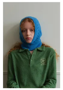 Detail of blue cable-knit balaclava with embroidered polo shirt showing brand logo
