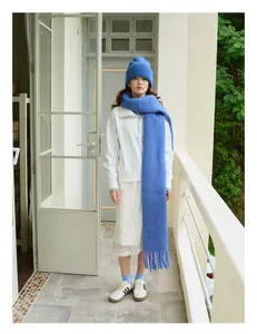 Detalle de gorro de lana azul real y conjunto de bufanda con flecos a juego en modelo
