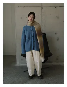 Dettaglio di sciarpa in misto lana sfumata con nappe e cardigan blu scuro su modella