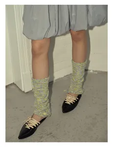 Detailed knit texture of colorful leg warmers in pale yellow and green with pointed flats