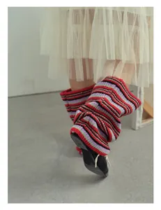 Close-up of striped wool knit leg warmers with layered tulle skirt and leather shoes