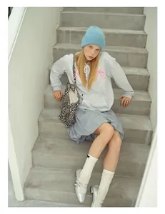 Street style view of a wool knit hat styled with a grey hoodie and a leopard print tote bag