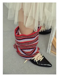 Detailed close-up of striped wool knit leg warmers paired with black pointed lace-up shoes