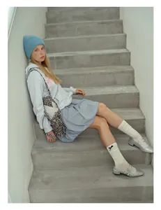 Detail of model wearing a blue knitted wool beanie with white slouch socks and bow accents